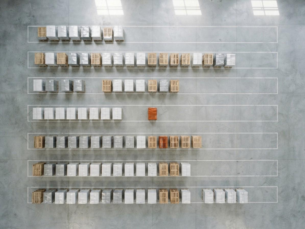 Pallets seen from above, arranged like a planning grid; one pallet is wrapped in orange.